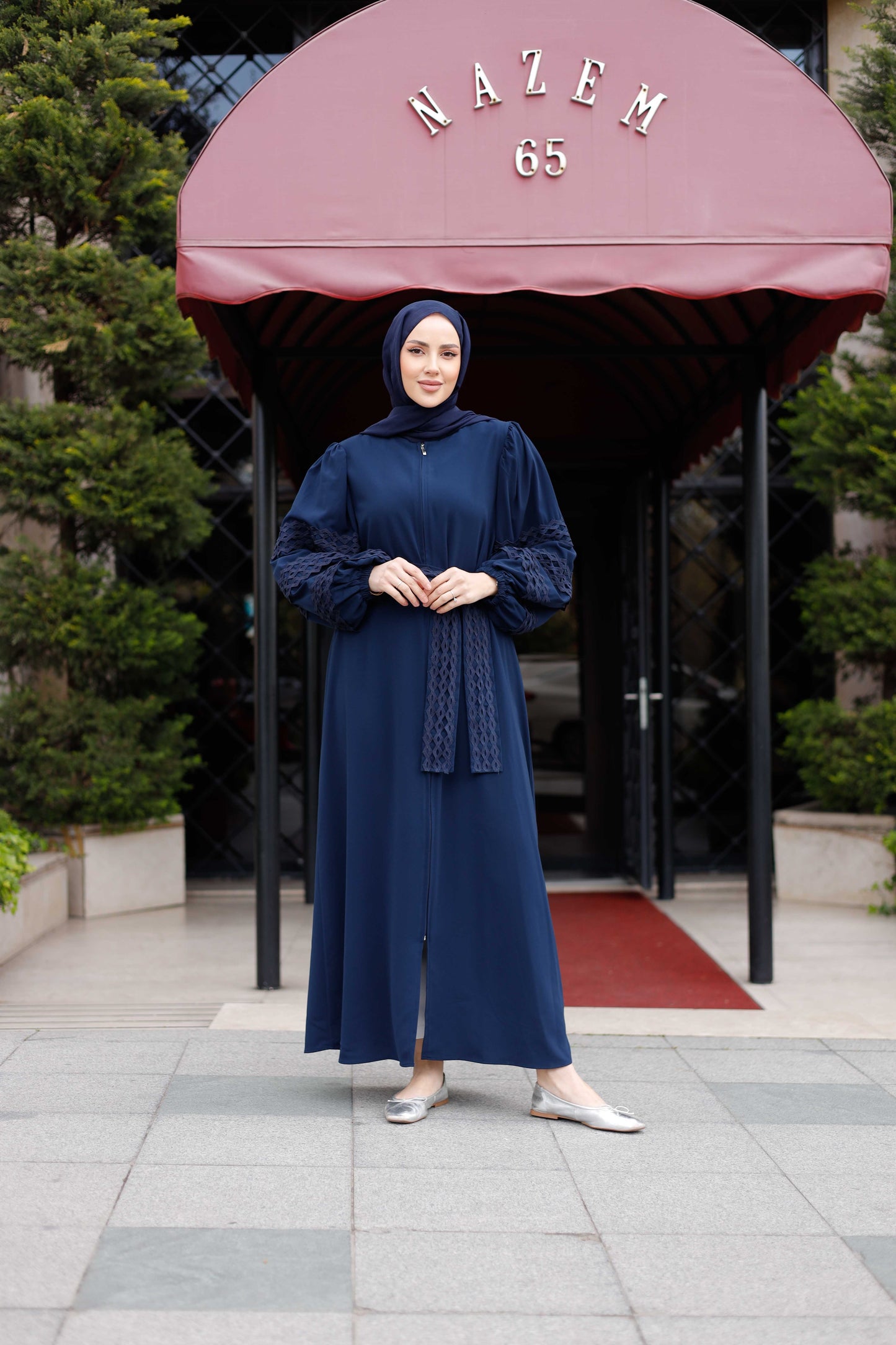 Elegant Medine İpeği ferace with lace details, model showcasing a stylish look in a navy blue outdoor setting.